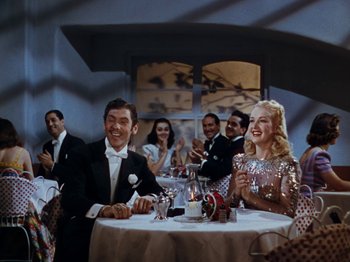 Movie still from “Down Argentine Way” (1940), directed by Irving Cummings – A group of people sitting at a table with wine glasses; Medium shot, High angle