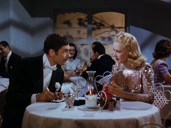 Movie still from “Down Argentine Way” (1940), directed by Irving Cummings – A man and a woman sitting at a dinner table; Medium shot, High angle