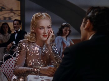 Movie still from “Down Argentine Way” (1940), directed by Irving Cummings – A woman in a sequined dress talking to a man in a suit; Medium shot, Over the shoulder angle