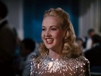 Movie still from “Down Argentine Way” (1940), directed by Irving Cummings – A woman with blonde hair wearing a silver dress; Close Up shot, Over the shoulder angle