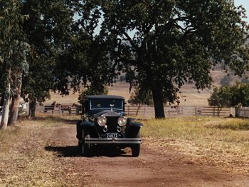 Movie still from “Down Argentine Way” (1940), directed by Irving Cummings – An old car parked on the side of a dirt road; Extreme Wide shot, High angle