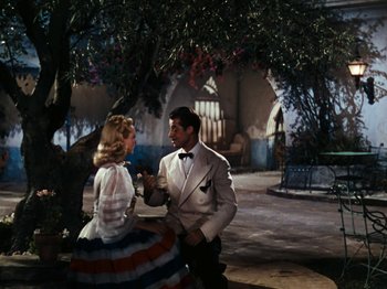 Movie still from “Down Argentine Way” (1940), directed by Irving Cummings – A man and a woman are talking in front of a tree; Wide shot, High angle