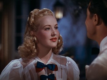 Movie still from “Down Argentine Way” (1940), directed by Irving Cummings – A woman with blonde hair wearing a white shirt and a bow tie; Close Up shot, Over the shoulder angle