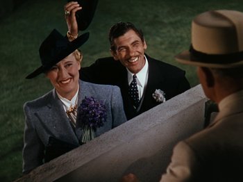 Movie still from “Down Argentine Way” (1940), directed by Irving Cummings – A man and a woman wearing suits and hats; Medium shot, High angle