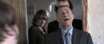 Movie still from “Down Terrace” (2009), directed by Ben Wheatley – An older man wearing a suit and a tie; Close Up shot, Low angle