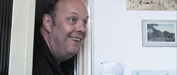 Movie still from “Down Terrace” (2009), directed by Ben Wheatley – A person with a smile on their face; Close Up shot, Over the shoulder angle