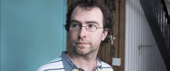 Movie still from “Down Terrace” (2009), directed by Ben Wheatley – A person wearing glasses and a striped shirt; Close Up shot, Low angle