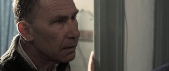 Movie still from “Down Terrace” (2009), directed by Ben Wheatley – An older man looking out of a window; Close Up shot, Over the shoulder angle