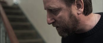 Movie still from “Down Terrace” (2009), directed by Ben Wheatley – A man's face as he looks down; Close Up shot, Over the shoulder angle