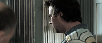Movie still from “Down Terrace” (2009), directed by Ben Wheatley – A person wearing glasses looking out a window; Close Up shot, Low angle