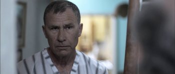 Movie still from “Down Terrace” (2009), directed by Ben Wheatley – An older man in a striped shirt looking at the camera; Close Up shot, Low angle