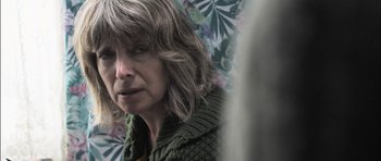 Movie still from “Down Terrace” (2009), directed by Ben Wheatley – A person wearing a green sweater; Close Up shot, Over the shoulder angle