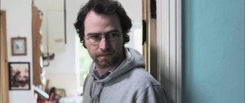 Movie still from “Down Terrace” (2009), directed by Ben Wheatley – A person wearing glasses and a hoodie; Close Up shot, Low angle