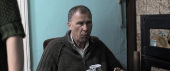 Movie still from “Down Terrace” (2009), directed by Ben Wheatley – A man sitting in front of a coffee cup; Close Up shot, Over the shoulder angle