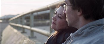 Movie still from “Down Terrace” (2009), directed by Ben Wheatley – A woman sitting next to a man in front of a railing; Close Up shot, Low angle