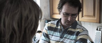 Movie still from “Down Terrace” (2009), directed by Ben Wheatley – A man with glasses is looking down at a woman; Close Up shot, Over the shoulder angle