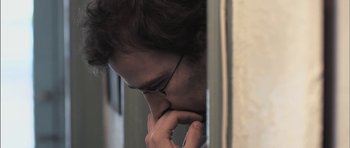Movie still from “Down Terrace” (2009), directed by Ben Wheatley – A man with glasses is leaning against a wall; Close Up shot, Over the shoulder angle