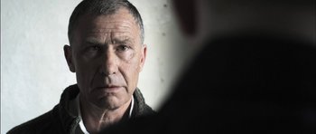 Movie still from “Down Terrace” (2009), directed by Ben Wheatley – An older man looking into a mirror with a serious look on his face; Close Up shot, Over the shoulder angle