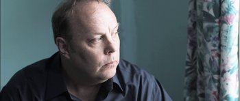 Movie still from “Down Terrace” (2009), directed by Ben Wheatley – A person wearing a blue shirt; Close Up shot, Low angle