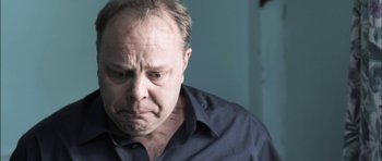 Movie still from “Down Terrace” (2009), directed by Ben Wheatley – An older man with a frowning look on his face; Close Up shot, Over the shoulder angle