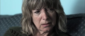 Movie still from “Down Terrace” (2009), directed by Ben Wheatley – An older woman is looking at the camera; Close Up shot, Over the shoulder angle