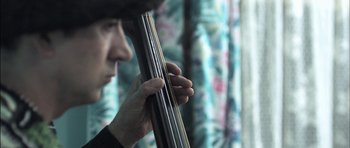 Movie still from “Down Terrace” (2009), directed by Ben Wheatley – A person holding a large metal object up to their face; Extreme Close Up shot, Low angle