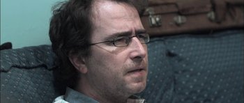 Movie still from “Down Terrace” (2009), directed by Ben Wheatley – A person wearing glasses; Close Up shot, Over the shoulder angle