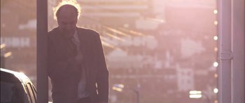 Movie still from “Down Terrace” (2009), directed by Ben Wheatley – A man in a suit standing in front of a stadium; Medium shot, Low angle
