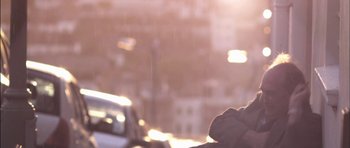 Movie still from “Down Terrace” (2009), directed by Ben Wheatley – A person standing in the rain near a street; Medium shot, Low angle