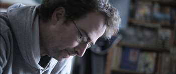 Movie still from “Down Terrace” (2009), directed by Ben Wheatley – A person wearing glasses looking down; Close Up shot, Low angle