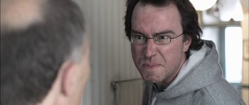 Movie still from “Down Terrace” (2009), directed by Ben Wheatley – A person wearing glasses looking at the camera; Close Up shot, Over the shoulder angle