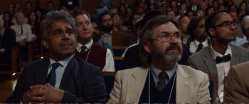 Movie still from “Downsizing” (2017), directed by Alexander Payne – A group of people sitting in front of an audience; Medium shot, Over the shoulder angle