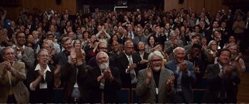 Movie still from “Downsizing” (2017), directed by Alexander Payne – A group of people sitting in a room clapping and applauding; Wide shot, Over the shoulder angle