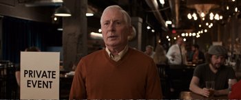Movie still from “Downsizing” (2017), directed by Alexander Payne – An older man wearing a brown sweater and a white shirt; Close Up shot, Over the shoulder angle