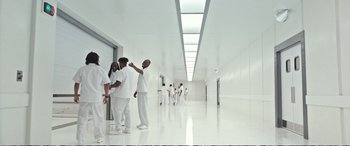Movie still from “Downsizing” (2017), directed by Alexander Payne – A group of doctors in a large white room; Wide shot, Low angle