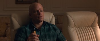 Movie still from “Downsizing” (2017), directed by Alexander Payne – A bald man sitting in a chair holding a cigarette; Close Up shot, Over the shoulder angle