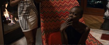 Movie still from “Downsizing” (2017), directed by Alexander Payne – A woman sitting in a chair eating something; Medium shot, Over the shoulder angle