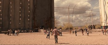 Movie still from “Downsizing” (2017), directed by Alexander Payne – A group of people standing on top of a dirt field; Extreme Wide shot, High angle