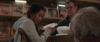 Movie still from “Downsizing” (2017), directed by Alexander Payne – A woman holding a plate in front of a man holding a box; Medium shot, Low angle