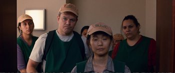 Movie still from “Downsizing” (2017), directed by Alexander Payne – A group of people standing next to each other wearing hats and aprons; Medium shot, Low angle