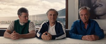 Movie still from “Downsizing” (2017), directed by Alexander Payne – A man sitting at a table with other people; Medium shot, Low angle
