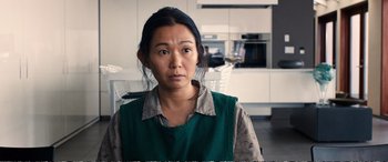 Movie still from “Downsizing” (2017), directed by Alexander Payne – A woman in a green shirt is standing in a kitchen; Close Up shot, Over the shoulder angle