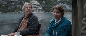 Movie still from “Downsizing” (2017), directed by Alexander Payne – A man and a woman sitting next to a body of water; Medium shot, Low angle