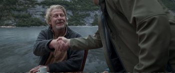 Two people shaking hands over a body of water