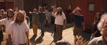 Movie still from “Downsizing” (2017), directed by Alexander Payne – A group of people standing in the dirt with their hands up; Wide shot, High angle