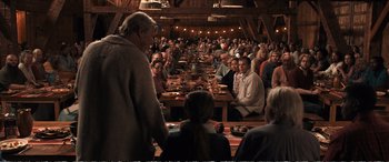 Movie still from “Downsizing” (2017), directed by Alexander Payne – A group of people sitting around a table eating food; Wide shot, Over the shoulder angle
