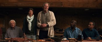 Movie still from “Downsizing” (2017), directed by Alexander Payne – A man and two women standing next to each other in front of food; Medium shot, Low angle