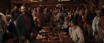 Movie still from “Downsizing” (2017), directed by Alexander Payne – A group of people sitting around a table with plates of food; Wide shot, High angle