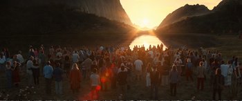 Movie still from “Downsizing” (2017), directed by Alexander Payne – A large group of people standing in front of a body of water at sunset; Extreme Wide shot, High angle