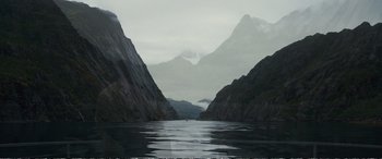 Movie still from “Downsizing” (2017), directed by Alexander Payne – A body of water surrounded by mountains and a cloudy sky; Extreme Wide shot, High angle